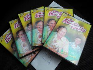 หลายคนแสดง DVD ไทยสีเหลืองเรื่อง 'จิตรกรรม ศรีและราศี เดือดไร้ที่สิ้นสุด' วางเรียงกันบนพื้นดำ