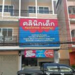 ป้ายสินค้าคลีนิกเด็กสีชมพูและฟ้าติดตั้งบนร้านค้าทำเลชั้นสองของอาคารพาณิชย์สี่ชั้นในพื้นที่ชุมชน
