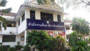 สถาบันการศึกษาสาขาทรงคณะวิทยาลัยอาคารขาวสองชั้นพร้อมป้ายวัฒนาการสีน้ำเงินและธงชาติต่างประเทศ