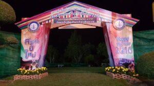 ประตูอนุสรณ์ขนาดใหญ่สีชมพูและม่วงตั้งไว้ในเขตราชการที่มีข้อความสวัสดีปีใหม่ 2016 และดอกไม้สีเหลืองประดับด้านข้าง