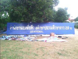 ป้ายสีน้ำเงินอาคารศูนย์วิทยาศึกษาบนพื้นดินกับวัสดุก่อสร้างและต้นไม้สีเขียวในพื้นหลัง