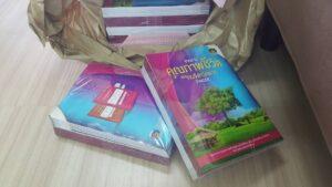 หนังสือเรียนภาษาไทยสองเล่มในถุงกระดาษสีเบจวางบนพื้นไม้สีอ่อน