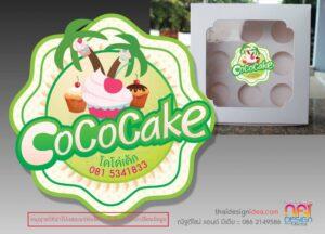 โลโก้และกล่องบรรจุภัณฑ์เค้กโคโค่ (CoCoCake) ที่มีการออกแบบสีเขียวสดใสพร้อมภาพประกอบเค้กคัพเค้กและผลไม้ตกแต่ง