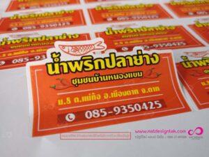 นามบัตรสีส้มของร้านนักพรักปลาเค็มชื่อ นักพรักปลาเค็มชูมชนบ้านหนองแบน พิมพ์ลวดลายปลาแดงและข้อมูลติดต่อ