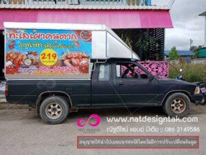 รถกระบะสีดำติดแผ่นฉากโฆษณาสัตว์ทะเลคนตากโดยร้านอาหารเคะไลเศษคนตาก