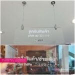 ป้ายรับสินค้า pick up ที่ติดตั้งบนเพดานร้านค้าด้วยสายเหล็กโครเมี่ยม มีข้อความในภาษาไทย อังกฤษ และญี่ปุ่น พร้อมโลโก้ร้าน DIFF