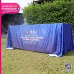 แบนเนอร์ส่งเสริมการขายสีน้ำเงินพร้อมข้อความสีขาวตั้งอยู่กลางแจ้ง แสดงข้อความของนวัตกรรมและการปรับปรุง โดยมีข้อมูลติดต่ออยู่ที่ด้านล่าง