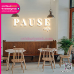 ร้านกาแฟ PAUSE CAFE ป้ายตัวอักษรไฟออกหลังสีขาวบนผนังสีเขียวพาสเทล