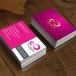 สองแสตก์ของนามบัตรสีชมพูมาเจนต้าที่มีโลโก้เลขแปดสีทองและลวดลายตาข่ายวางบนพื้นผิวไม้สีน้ำตาล
