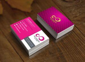 สองแสตก์ของนามบัตรสีชมพูมาเจนต้าที่มีโลโก้เลขแปดสีทองและลวดลายตาข่ายวางบนพื้นผิวไม้สีน้ำตาล