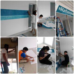กลุ่มคนกำลังปรับปรุงและตกแต่งห้องเรียนด้วยวอลเปเปอร์สีฟ้าและกิจกรรมศিลปะ