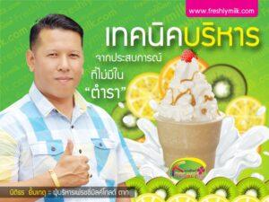 ชายคนหนึ่งแต่งตัวสุภาพแล้วยิ้มให้กับกล้องขณะชี้นิ้วขึ้น บนพื้นหลังสีเขียว โดยมีภาพของเค้กไอศครีมโทนสีขาว ตกแต่งด้วยสตรอว์เบอร์รี่ มะนาว และเกสรทอง พร้อมด้วยผลไม้สด เช่น กีวี่และมะนาวแกะเป็นสไลด์