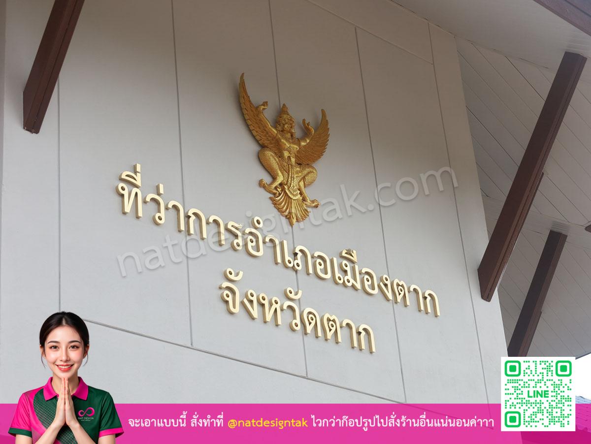 ป้ายตัวอักษรสแตนเลสสีทองบนผนังสีขาว